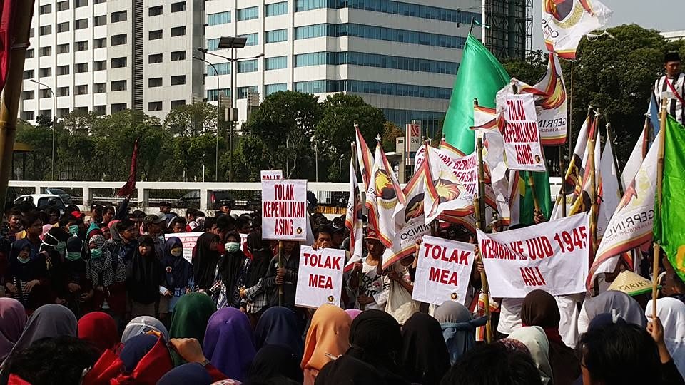 Kerumunan peserta aksi dengan spanduk dan bendera