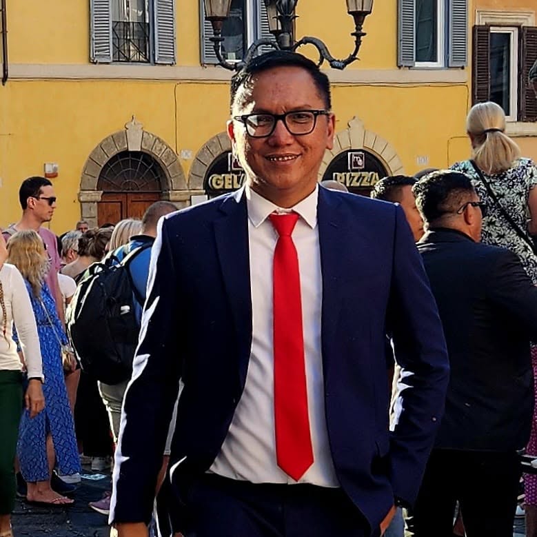 Bastian P. Simanjuntak mengenakan jas biru tua dan dasi merah